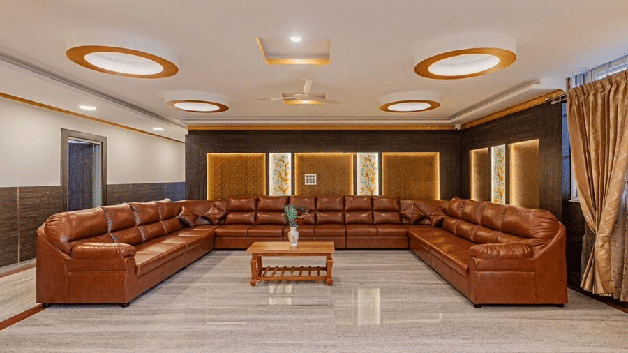 Luxurious lounge space with brown leather sofas, circular ceiling lights at Siri Ambari Resorts and Spa.