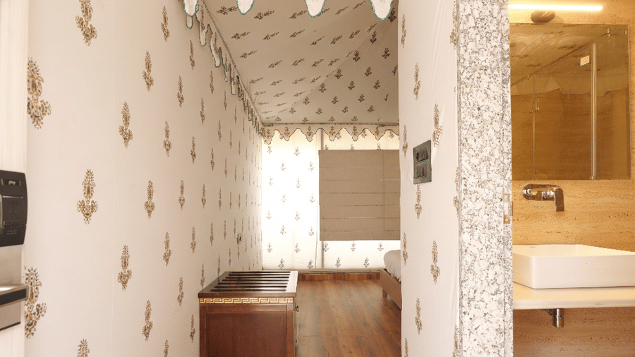 A room at Grassfield Riviera Resort, featuring a table placed infront of a checkered wall, and a connection to the bathroom showcasing a sink, and a water tap.
