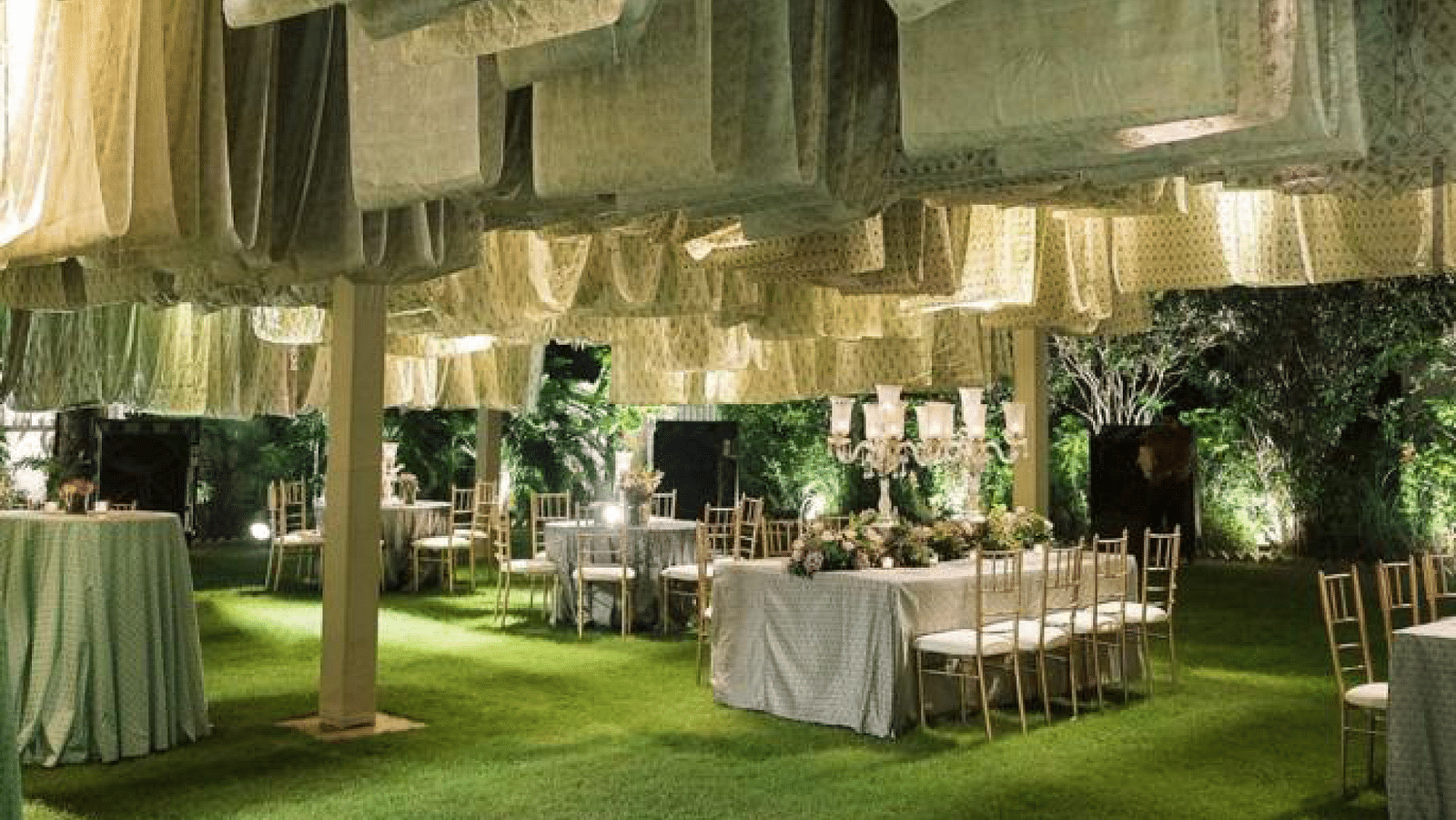 Banquet party on the green lawns, pictured with fancy cloth decorations and table and chairs celebrated in white - Saraca Hotels and Resorts