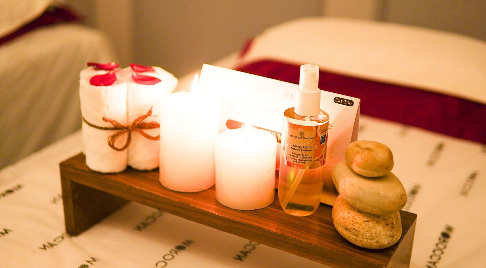 A closeup shot of candles next to a bathroom freshener and hand towels