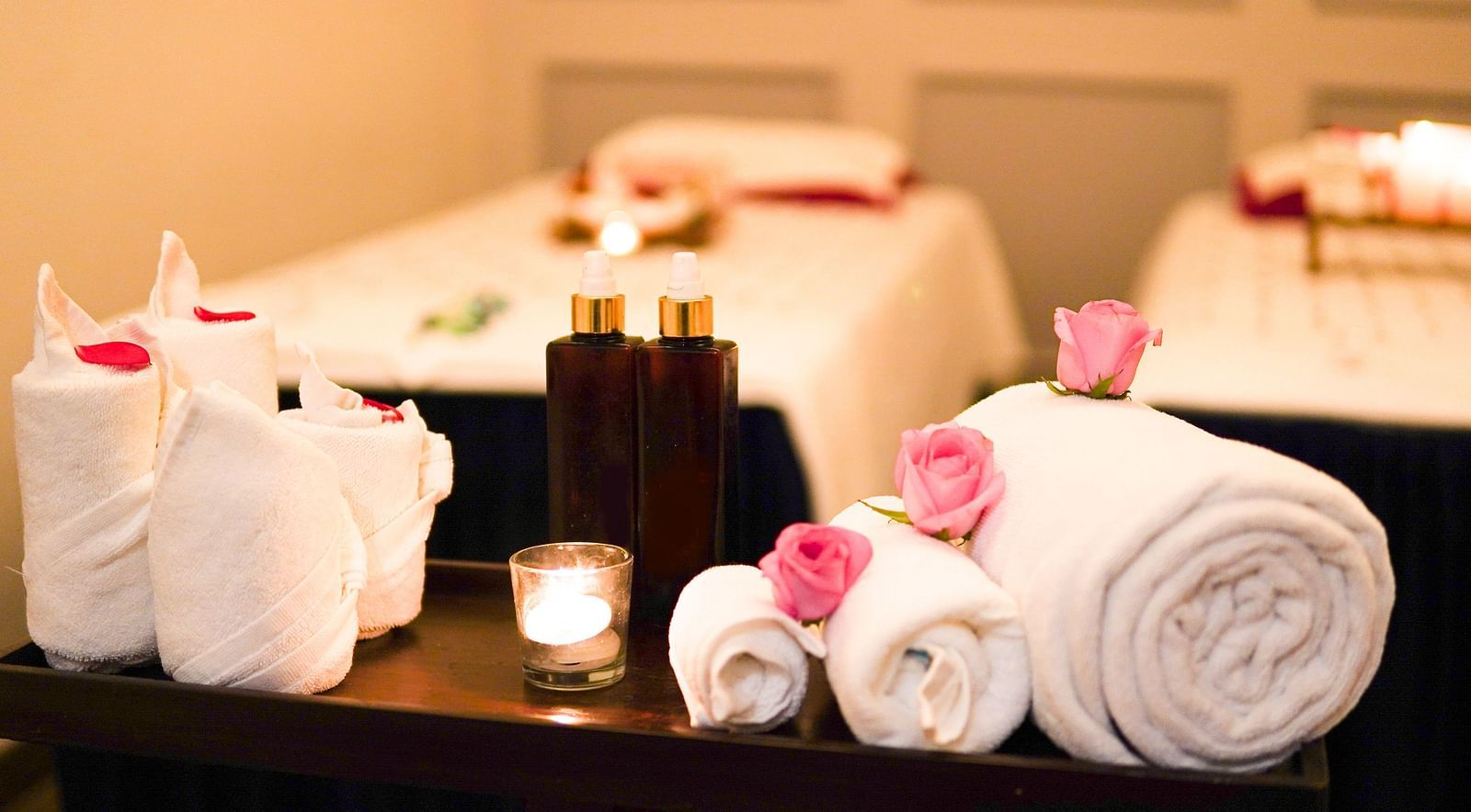 Image of towels beautifully wrapped and placed next to a candle and two bottles of essential oils