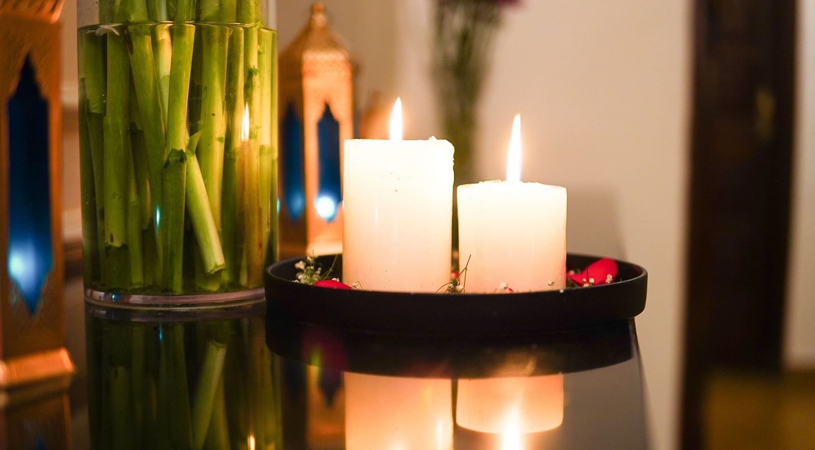 A close-up shot of two candles placed next to a mini bamboo plant