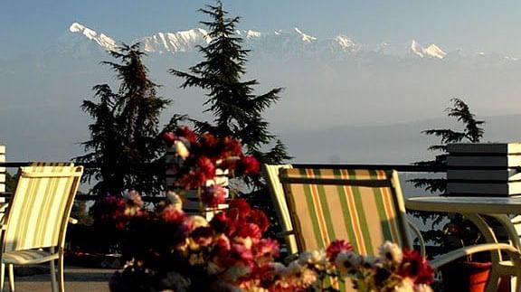 Outdoor seating area with umbrellas and plants, overlooking a breathtaking mountain view.