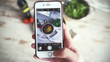 Person using a smartphone to capture an outdoor food photo.