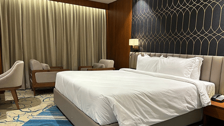 A spacious premium room featuring a king bed and a comfortable lounge area by the window - Praveg's Grand Eulogia, Ahmedabad