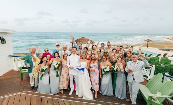 Large wedding party and guests pose on a deck overlooking the ocean at Abaco Inn.