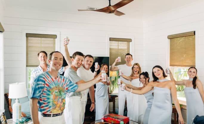 Group of people hold drinks and pose together in a room at Abaco Inn during a wedding event.
