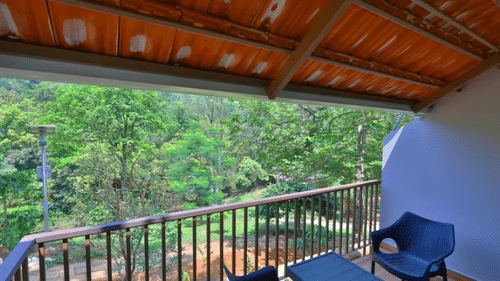 A balcony with a view of lush trees includes a seating area, offering a relaxing outdoor space. - Abad Brookside Lakkidi, Wayanad