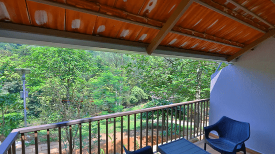 A balcony with a view of lush trees includes a seating area, offering a relaxing outdoor space. - Abad Brookside Lakkidi, Wayanad