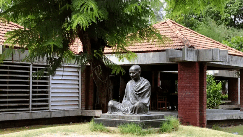 An exterior view of the Gandhi Ashram, featuring a large statue of Mahatma Gandhi in a seated posture, symbolising peace and contemplation.