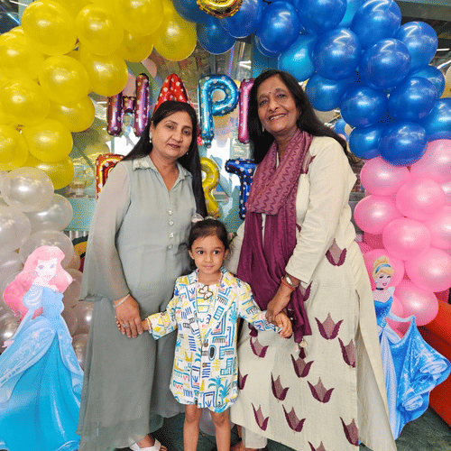 A family posing at a child's birthday party with colourful balloon decor at Central Courtyard Boutique Hotel.