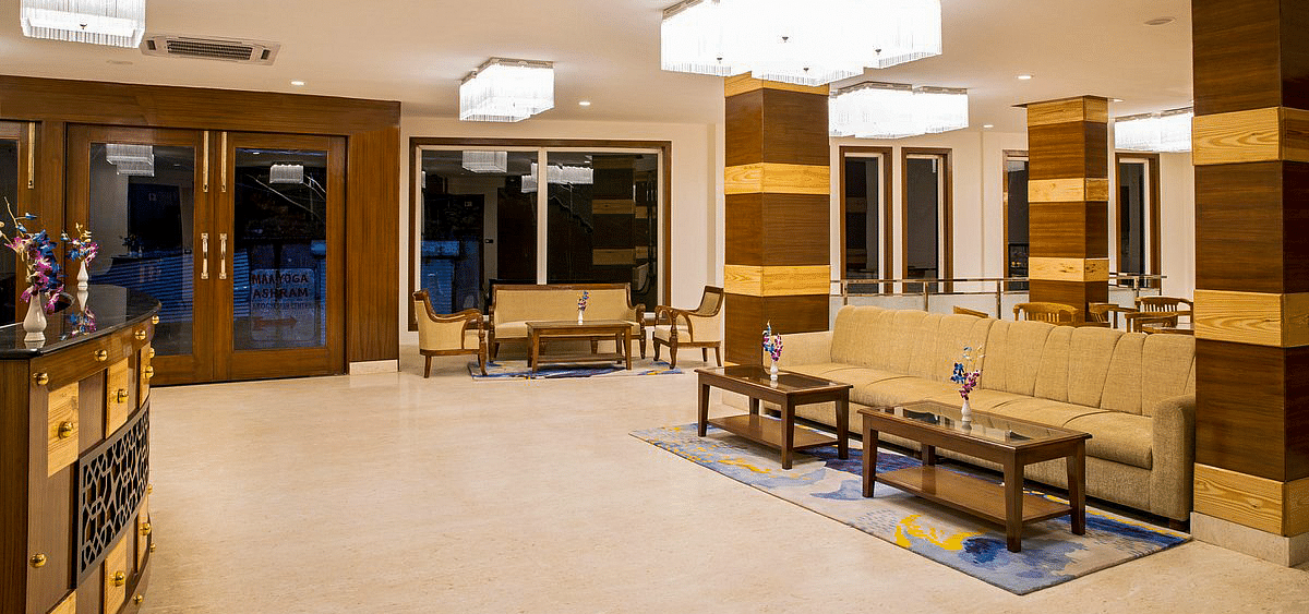 Corner view shot of the expansive lobby at Regenta Inn DLS with beige coloured couches kept in the waiting area.
