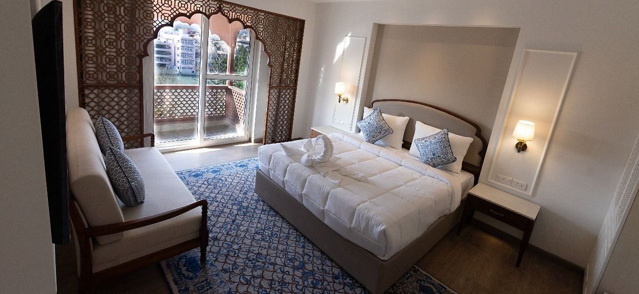 Top view shot of the Jalrupa Room featuring a double bed and a small balcony with huge french windows at Bhagirathi by RDB Atishay.
