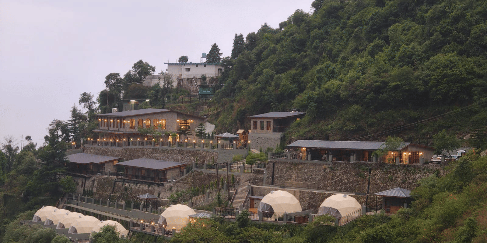 Panoramic view of Samsara Hill Resort nestled amidst the lush green hills of Mussoorie, showcasing the resort’s tranquil mountain setting.