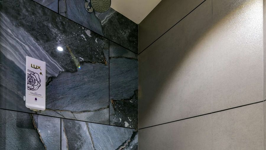 A shower area with warm lighting, featuring fully tiled walls and floor at Indie Stays, BKC Kalina.