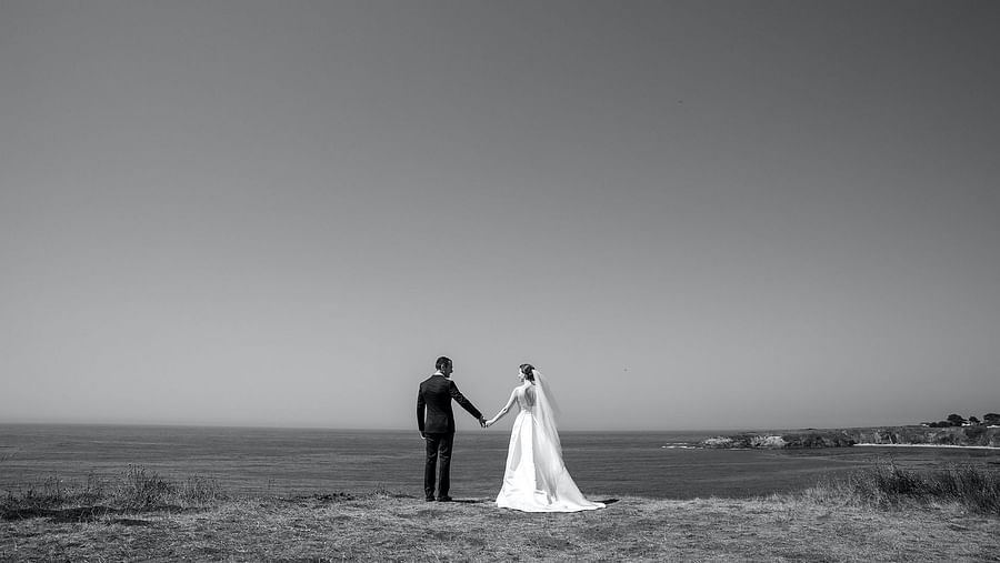 A Grayscale image of a Couple standing on a cliff, gazing into the distance