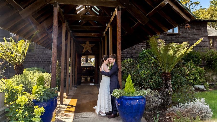 A rustic cottage framing a newlywed couple embracing each other