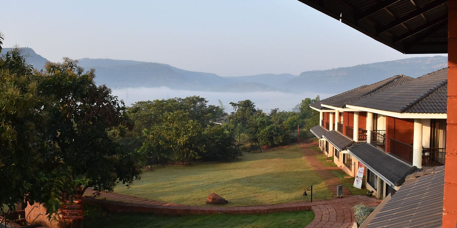 a ground-level view at Forest Escape resort, featuring buildings and a pathway surrounded by lush greenery.