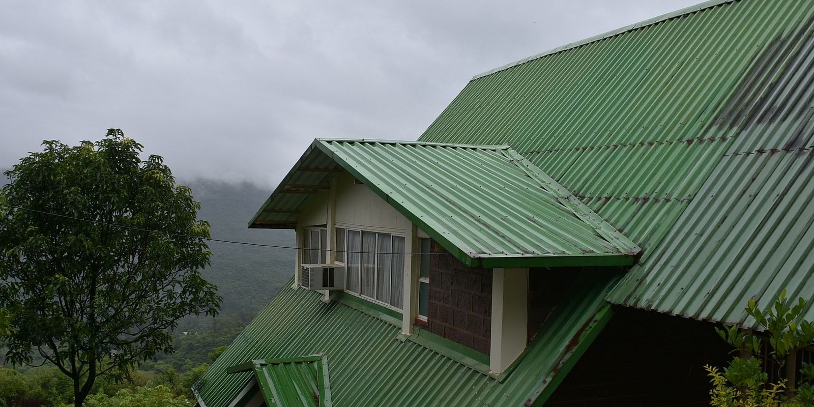 View of the roof of Wind Chalet Resort, surrounded by lush trees in the background.
