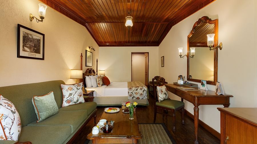 A well decorated room with a large bed, a shiny mirror alongside a make up table, a sofa that could spaciously seat three, with multiple wall decors and lights  - The Naini Retreat, Nainital