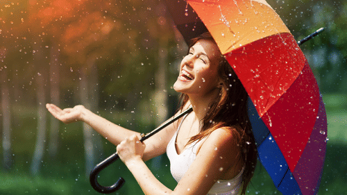 a woman holding a colourful umbrella and laughing