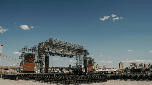 Empty outdoor stage set up on a sandy ground under a clear sky