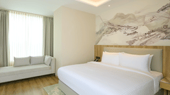 The hotel bedroom with a large bed and a daybed at Riviera Sarovar Portico, Pathankot.