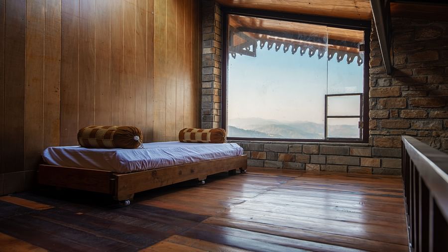 Rustic wooden bedroom interior with a bed and mountain view through a large window. - Blusalzz Homes The Himalayan Bungalow, Almora