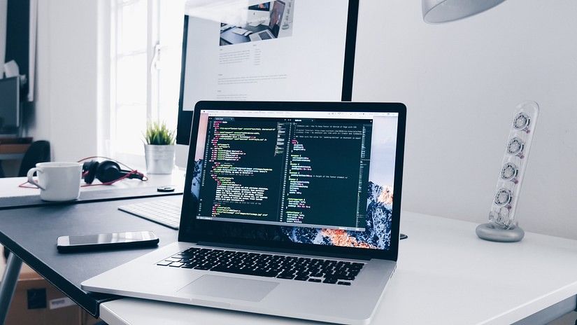 a Laptop on a desk with a monitor in the background