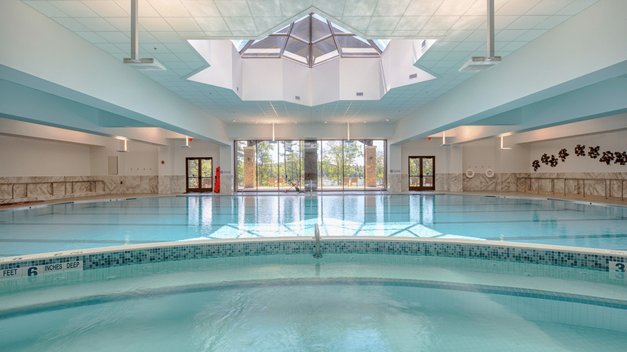 The Olympic-sized indoor swimming pool with a pyramid skylight and large glass doors at YO1 Longevity & Health Resorts, Catskills
