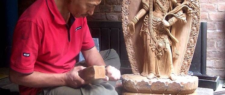 An overview of a man sculpting an idol from wood with accurate hits of the hammer.