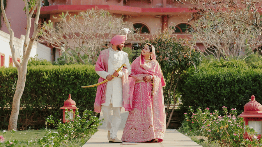 Jaswinder and Ritika standing before grand Umaid Palace building surrounded by greenery.