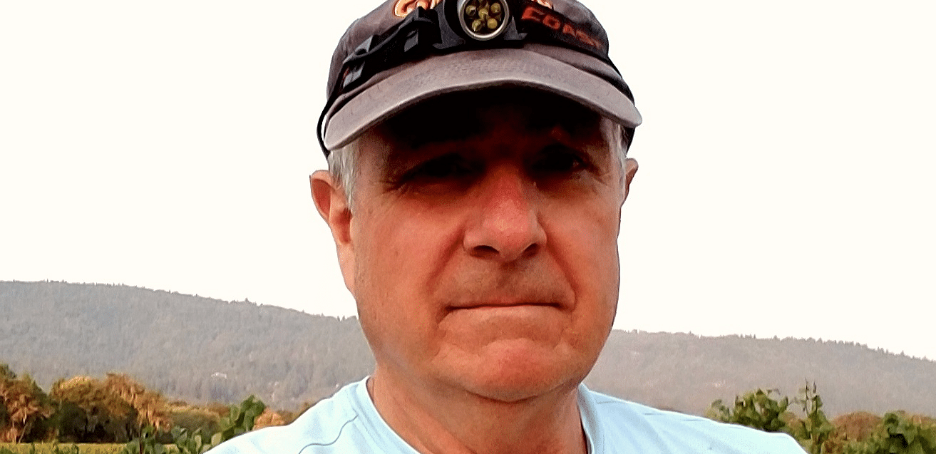 A man with a hat, wearing a t-shirt covered with dirt.