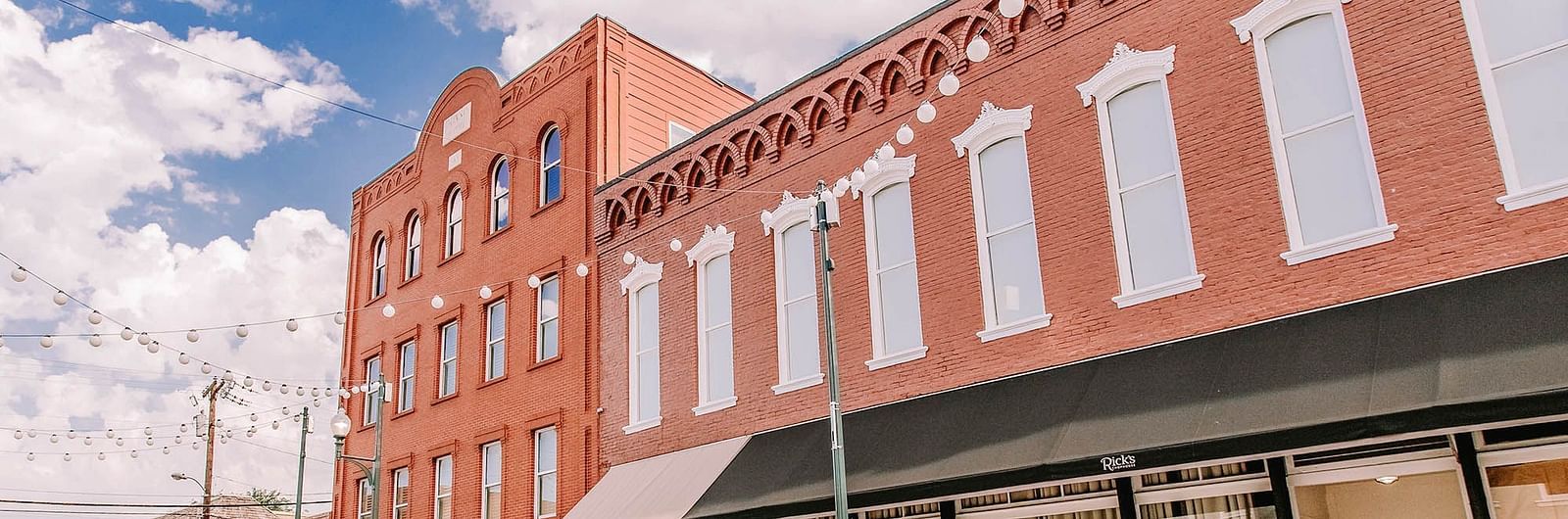 A brick building with large windows, a awning, and a quiet street.- The Grand Hotel & Ballroom, McKinney