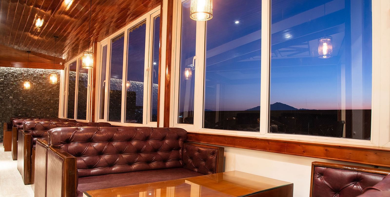 A seating arrangement of a bar in gangtok with leather couches and a well furnished table - Summit North Star, Gangtok