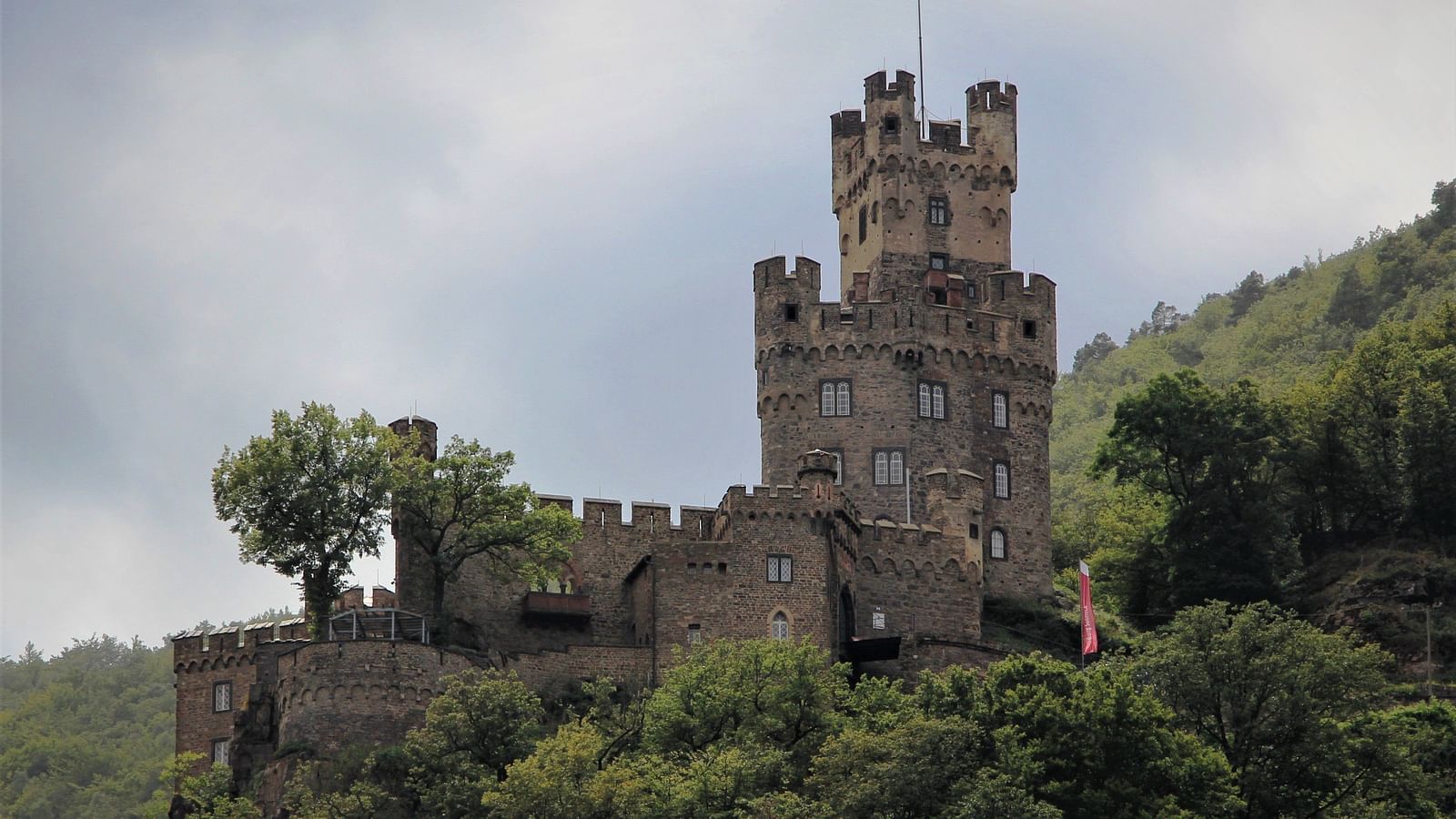 An overview of a ancient castle on a hilltop surrounded by greenery.