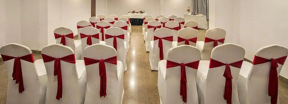 Banquet hall setup featuring  ample seating arrangement, bright lighting, and wooden flooring at Lords Eco Inn Jayanagar Bangalore.