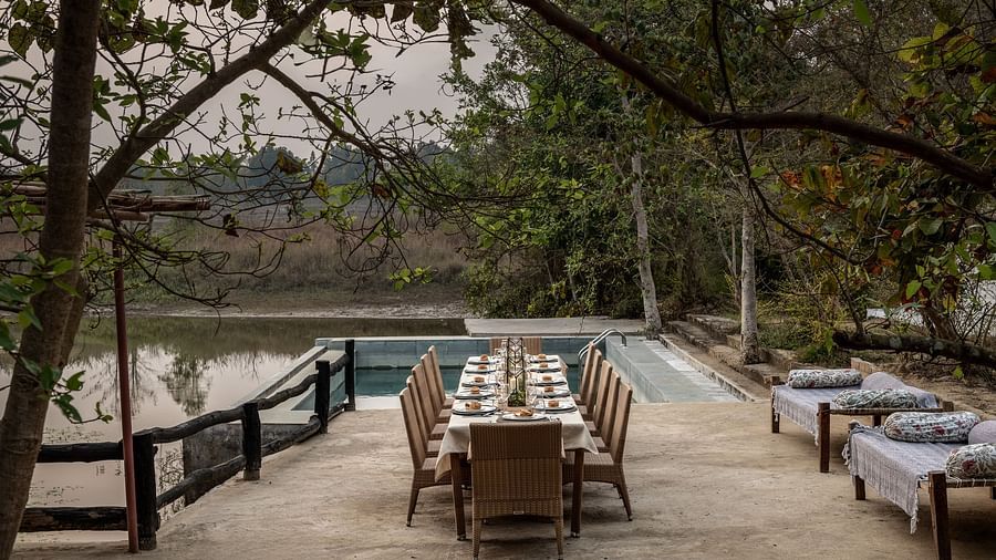 Dining setup neat Swimming Pool with a frame of beautiful trees at Saccharum Safari Lodge, Balaghat