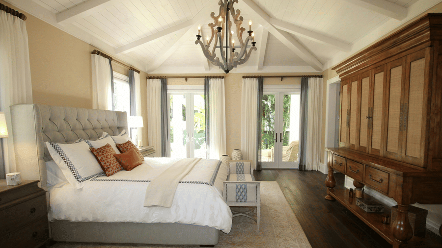 Side view image of the bed with a chandelier hanging over the double bed.