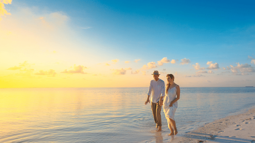 A couple walking alongside the beach holding hands