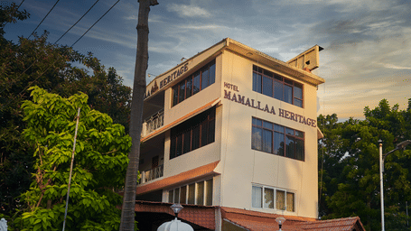 The exterior of Hotel Mamallaa Heritage from a slightly different angle, showcasing its multi-story structure and architectural details under a pleasant sky