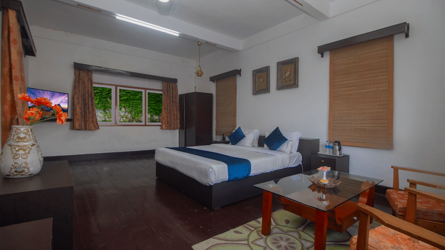 The Club King Room of Central Gleneagles Heritage Resort showcasing a double bed, wooden flooring,  seating area, and windows.