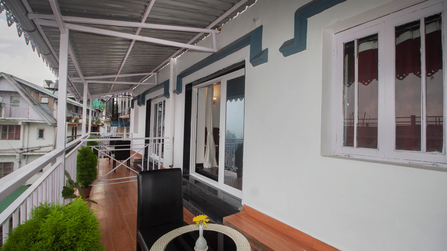 Open-air balcony with wooden railings, potted plants, and a view of the surroundings.