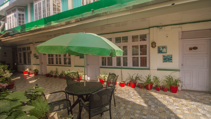 A dining set up with chair and table outside a building with an umbrella in the centre
