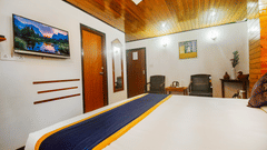 An image of a bedroom featuring a bed, chairs, a table with tea and coffee maker, and a mirror attached on the wall at Central Hill Resort, Gangtok