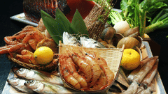 An assortment of cooked seafood, including fish, scallops, and shrimp, arranged on a large platter with lemons and leafy greens.