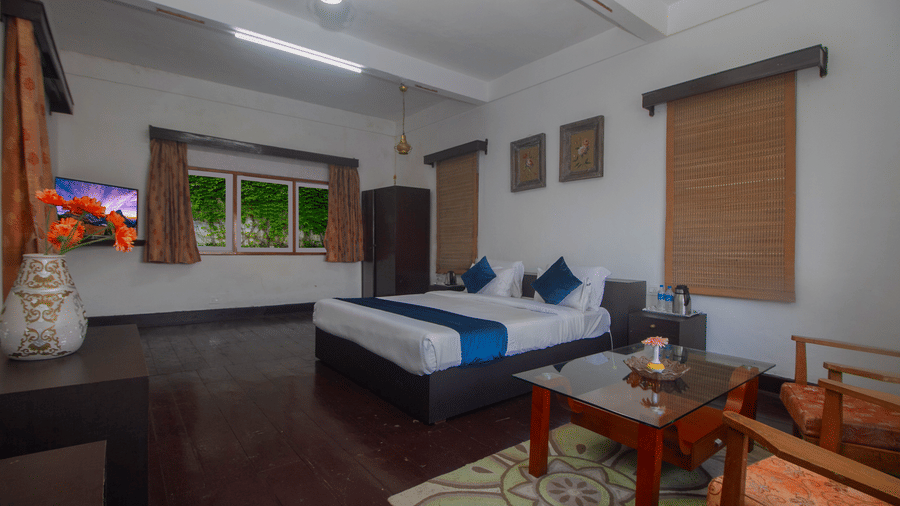 The Club King Room of Central Gleneagles Heritage Resort showcasing a double bed, wooden flooring,  seating area, and windows.