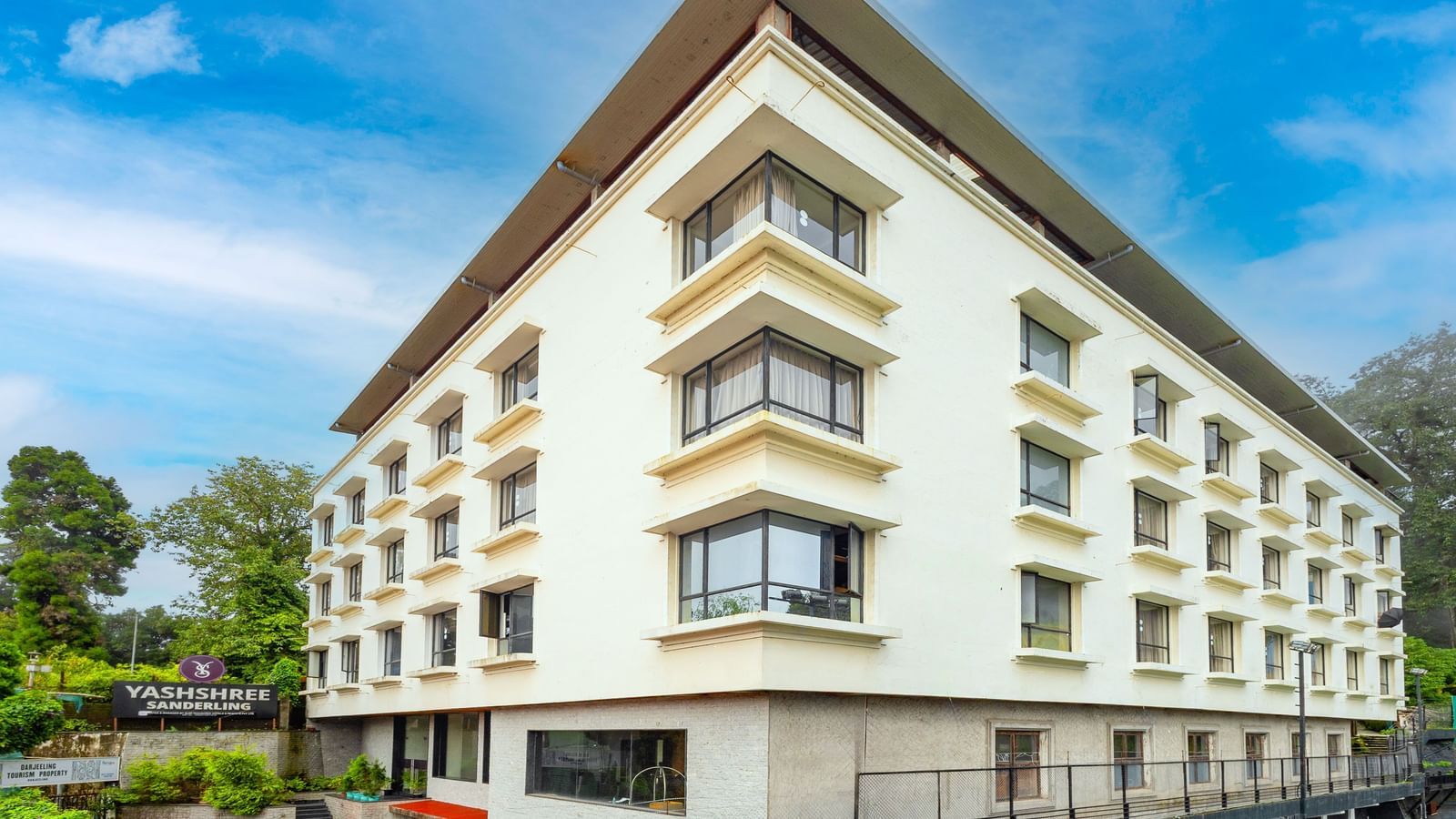 Front facade of Yashshree Sandelring, a modern multi-storey hotel in Darjeeling, surrounded by greenery and offering a stylish architectural design.