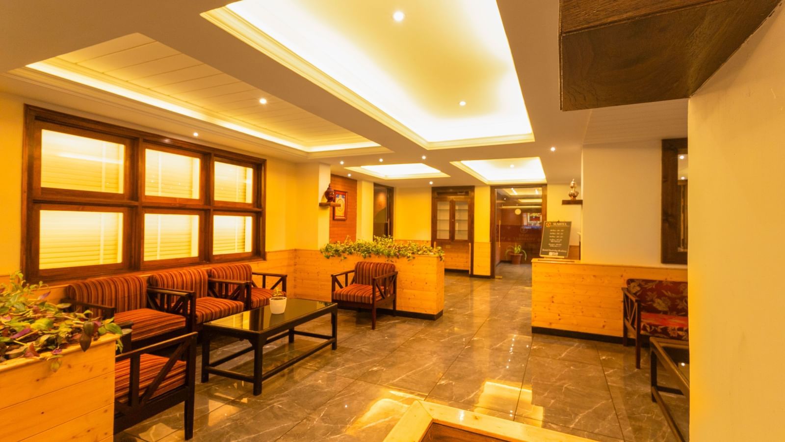 Bright lounge with wooden interiors and cosy chairs at Sumitel Premier Inn, Siliguri.