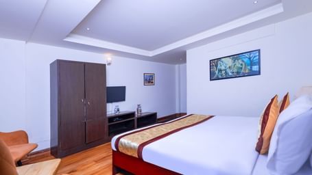 Guest room at Sumitel Premier Inn, Siliguri, with a cosy double bed, wooden interiors, and modern furniture creating a bright and welcoming stay atmosphere.